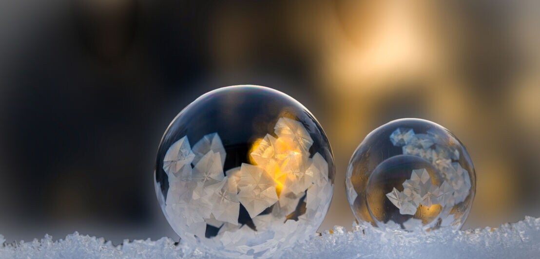 Zwei Seifenblasen, auf denen sich Eiskristalle bilden