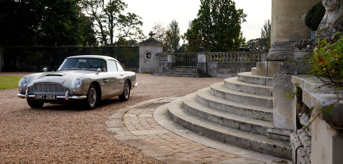 Ein silbergrauer Aston Martin DB5 von vorne links fotografiert.