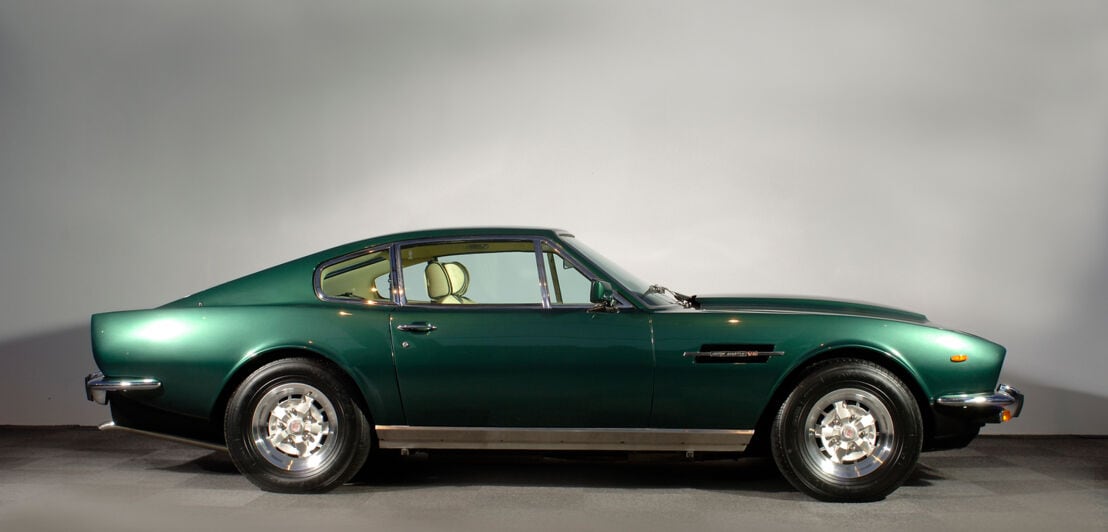 Ein dunkelgrüner Aston Martin V8 von der Seite im Studio.