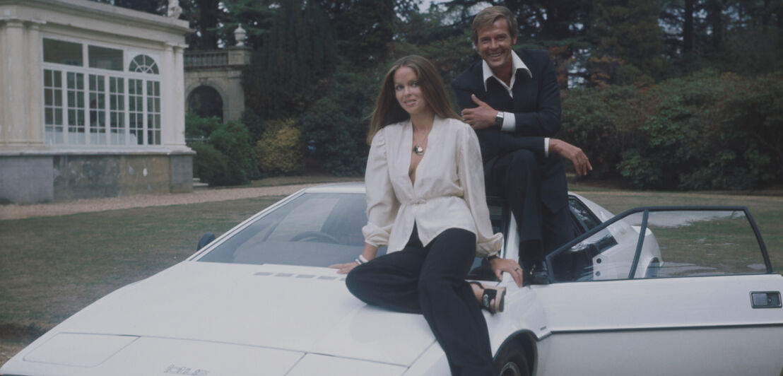 Barbara Bach und Roger Moore posieren mit einem weißen Lotus Esprit S1.