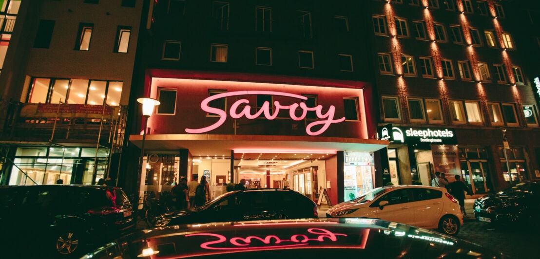 Kino von außen im Dunkeln mit beleuchtetem Savoy-Schriftzug