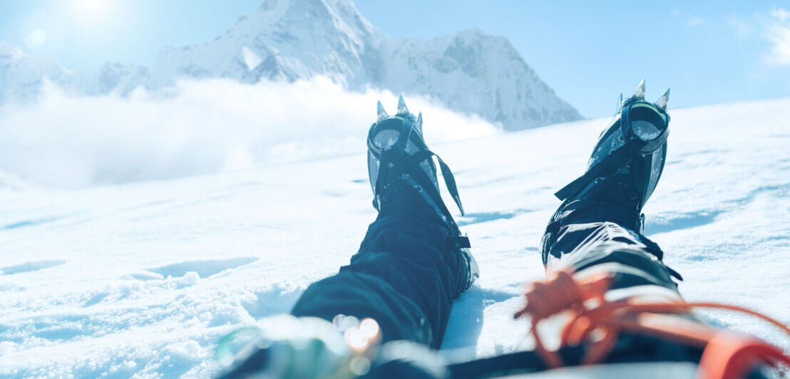 Beine und Füße einer bergsteigenden Person, im Schnee liegend