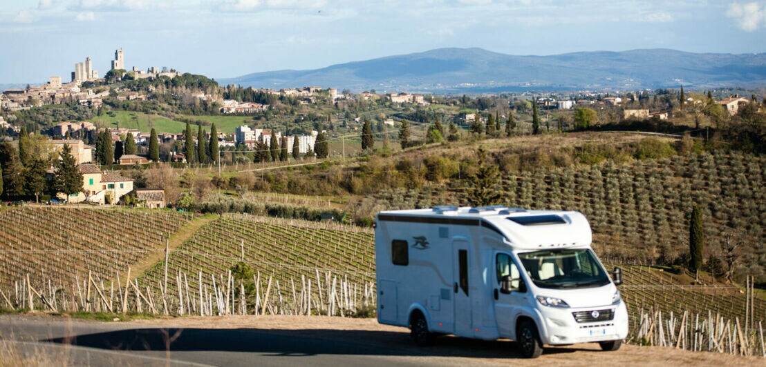 Ein Wohnmobil steht auf einer Straße vor der Skyline von San Gimignano