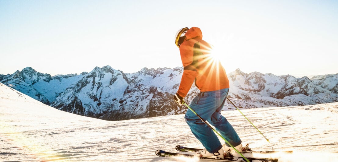 Ein Skifahrer fährt über eine sonnige Piste.