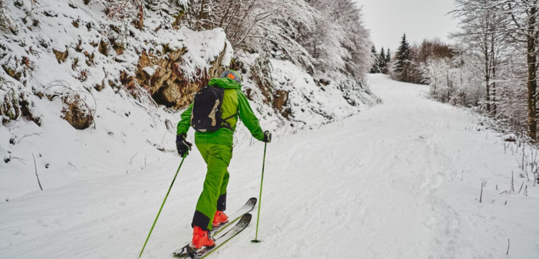 Eine Person in grüner Kleidung beim Skitourengehen