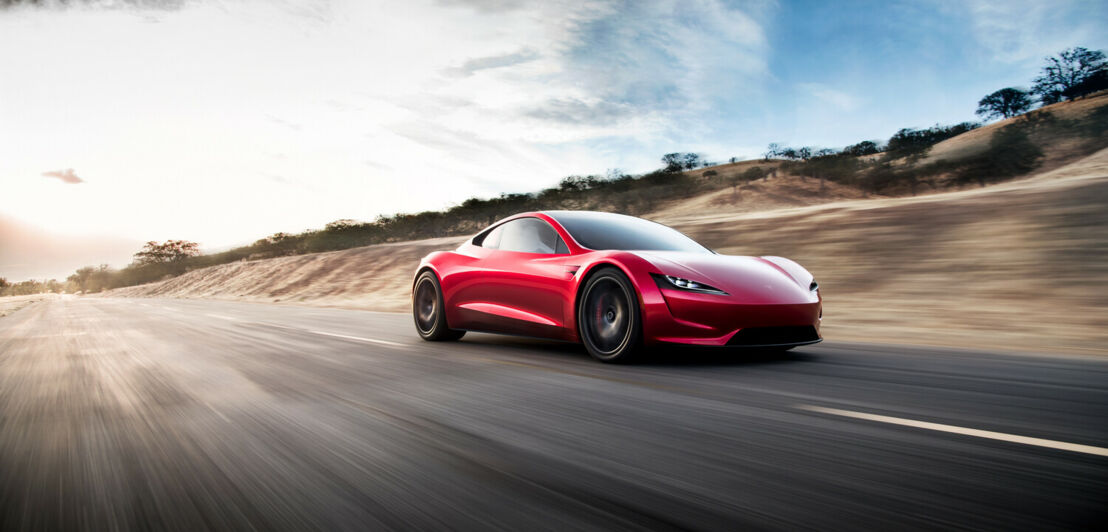 Ein roter Elektrosportwagen von Tesla fährt auf einer Straße.