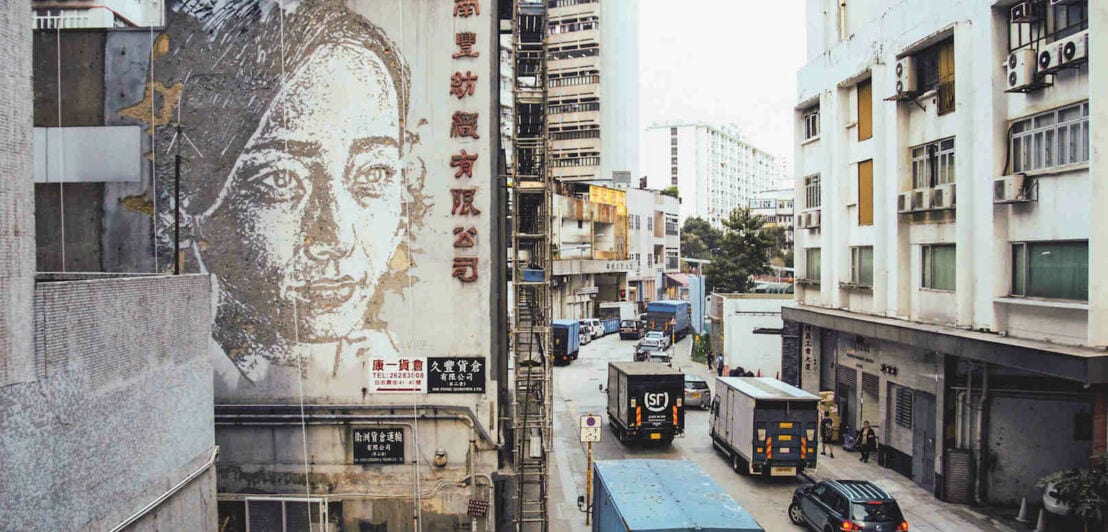 Ein, in den Putz gekratztes, Porträt einer Frau an einer Gebäudefassade in Hong Kong des Street-Art Künstlers Vhils. 