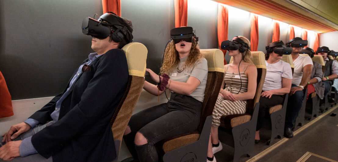 Personen mit Virtual-Reality-Brille in einer Buskulisse