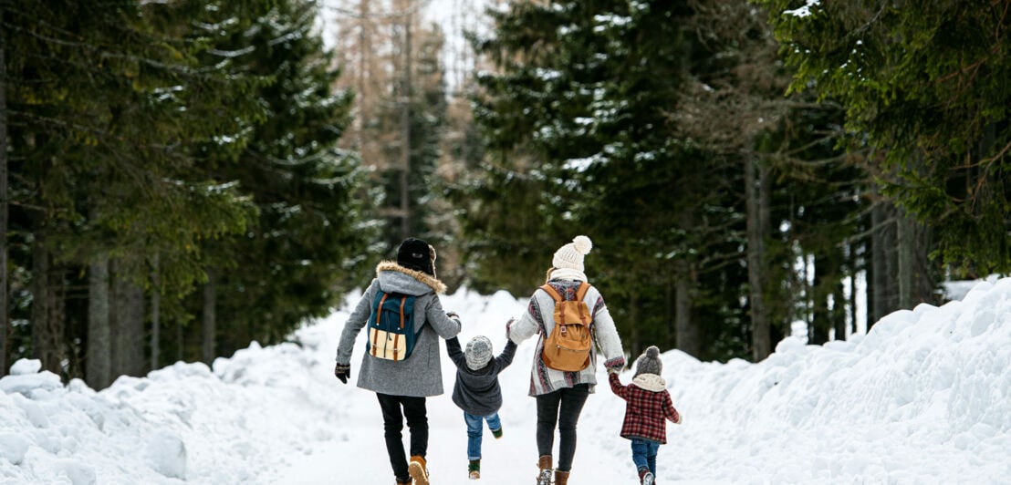 Familie mit Kindern im schneebedeckten Wald