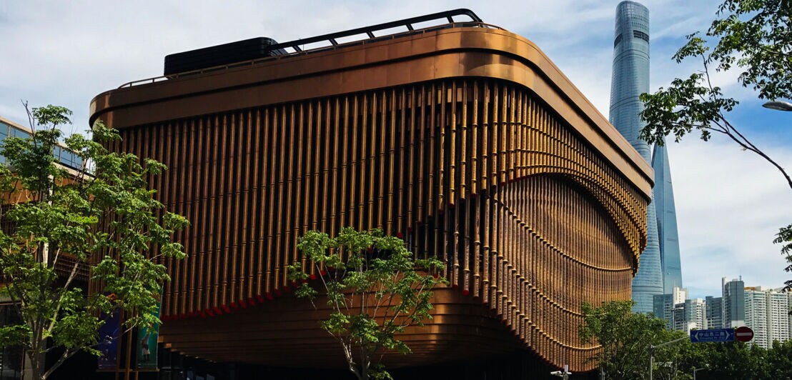 Modernes Gebäude mit Fassade aus beweglichen, goldfarbenen Stahlrohren im Zentrum von Shanghai