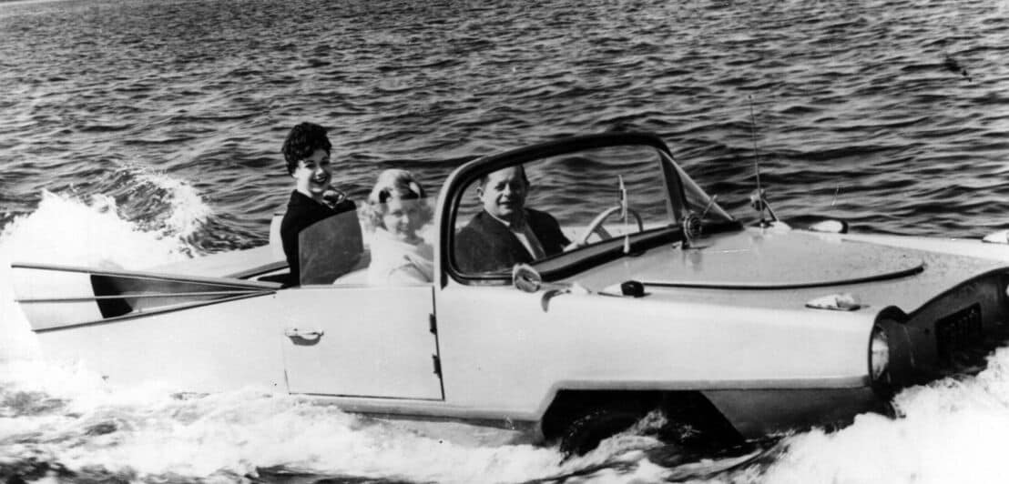 Ein Schwarz-Weiß-Foto eines Amphibienautos mit drei Personen an Bord