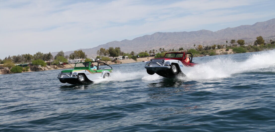 Zwei Amphibienautos fahren über das Wasser