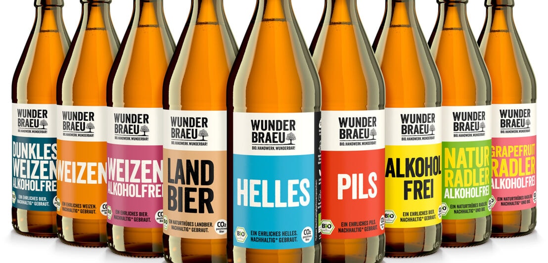 Neun aufgereihte Bierflaschen mit bunten Labels