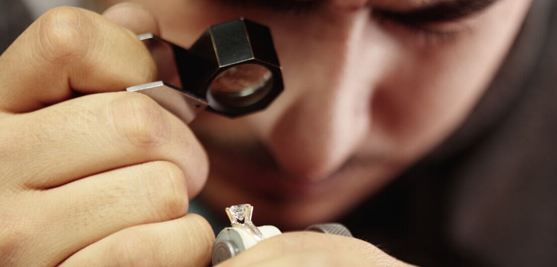 Ein Mann untersucht mit einer Lupe einen Diamanten