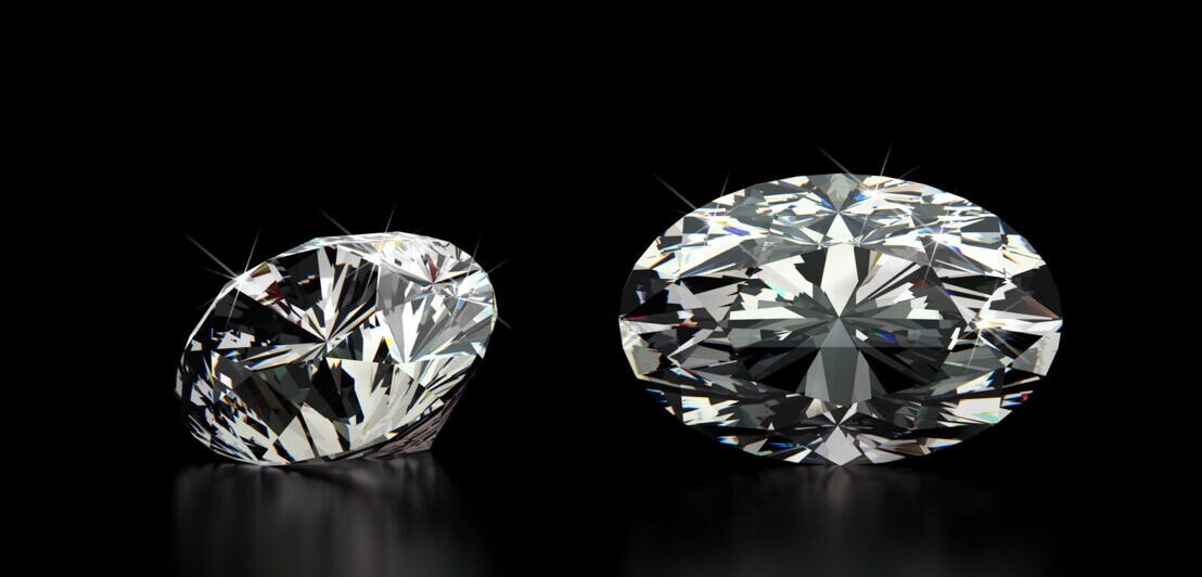 Zwei Diamanten mit Ovalschliff vor einem schwarzen Hintergrund.