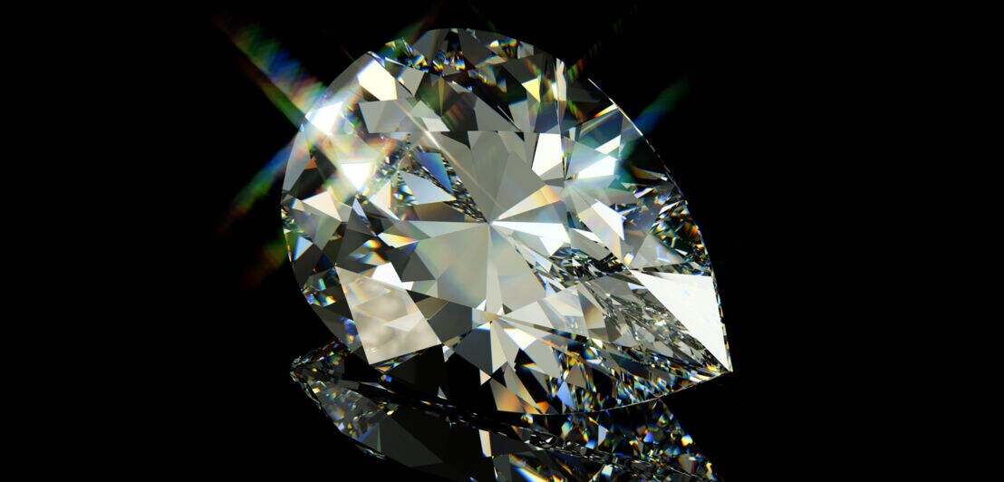 Ein Diamant im Tropfenschliff auf schwarzem Hochglanz-Hintergrund.
