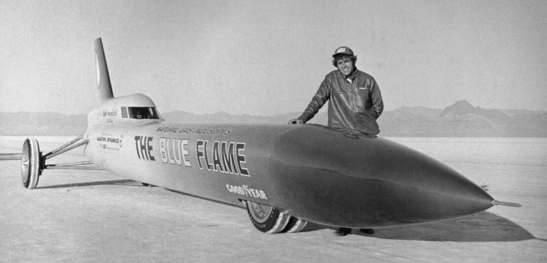 Historische Aufnahme des Rennwagenfahrers Gary Gabelich neben seinem Auto The Blue Flame