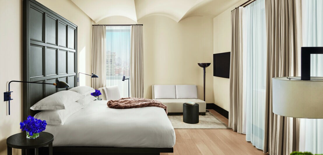 Hotelzimmer in hellen Farben, im Mittelpunkt ein Bett