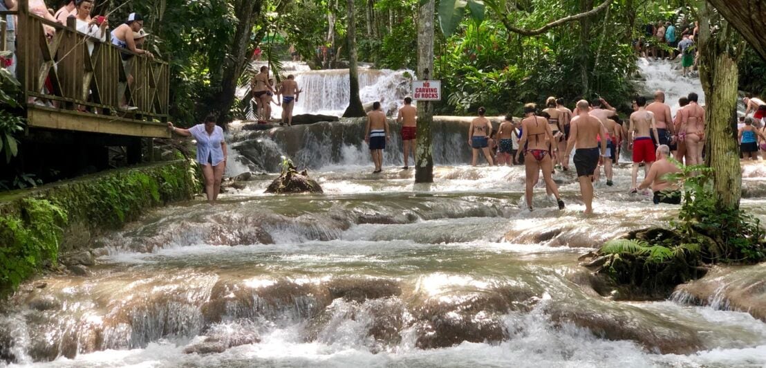 Ein stufenförmig hinablaufender Fluss, darin badende Menschen