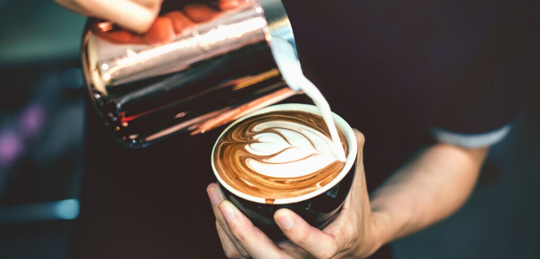 Ein Barista verziert einen Cappuccino mit einem hübschen Motiv