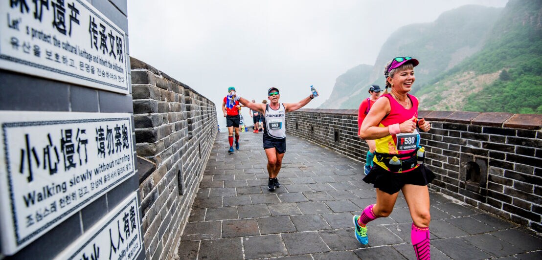 Jogger und Joggerinnen laufen über einen asphaltierten Weg in China beim Great Wall Marathon 2019.