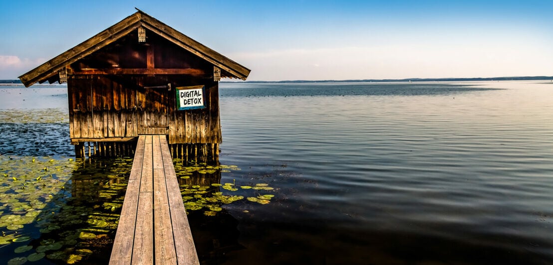 Kleine Holzhütte auf einem See, auf einem Schild steht „Digital Detox“