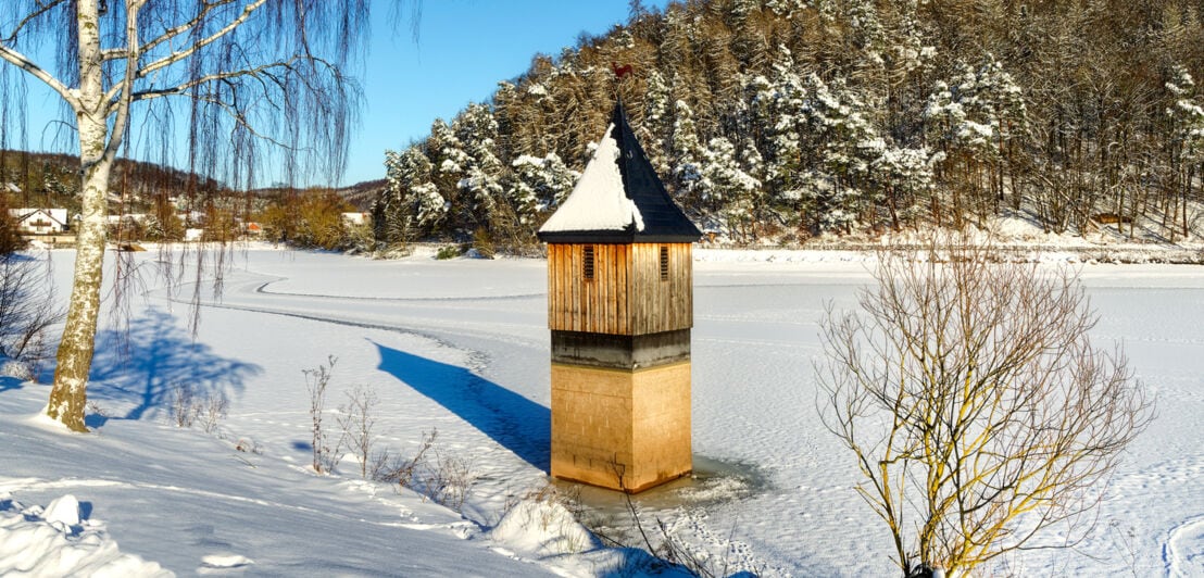 Eine Kirchturmspitze ragt aus dem zugefrorenen Wasser
