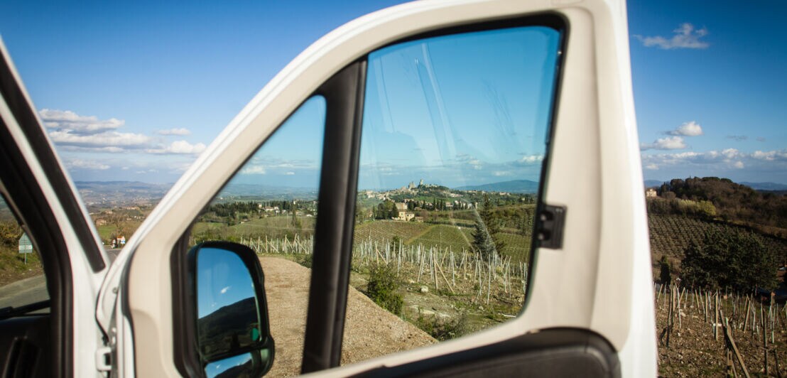 Blick durch eine Autotür auf San Gimignano