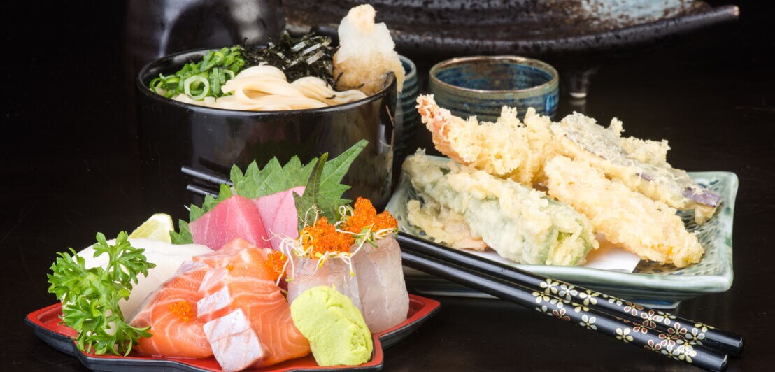 Drei japanische Gerichte auf kleinen Tellern angerichtet.