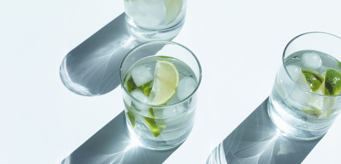 Gin Tonic im Glas mit Eiswürfeln und Limette.