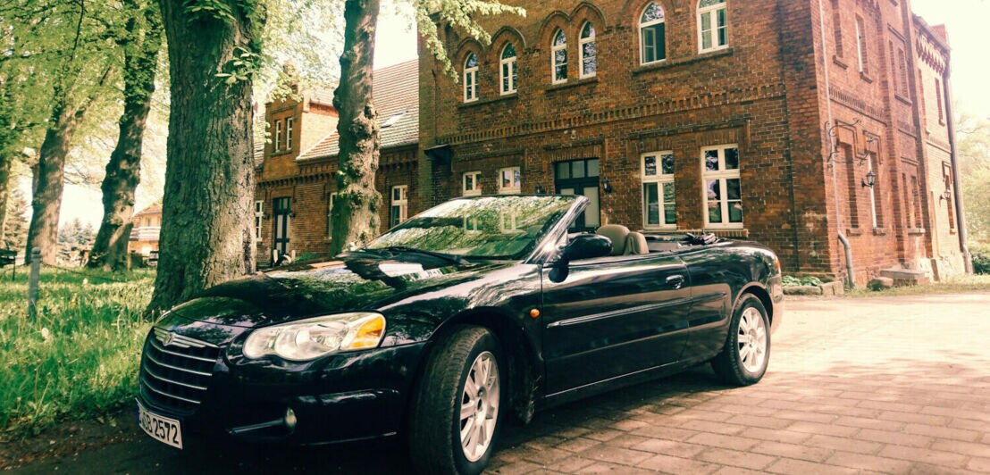 Ein schwarzes Cabrio vor einem alten Gebäude