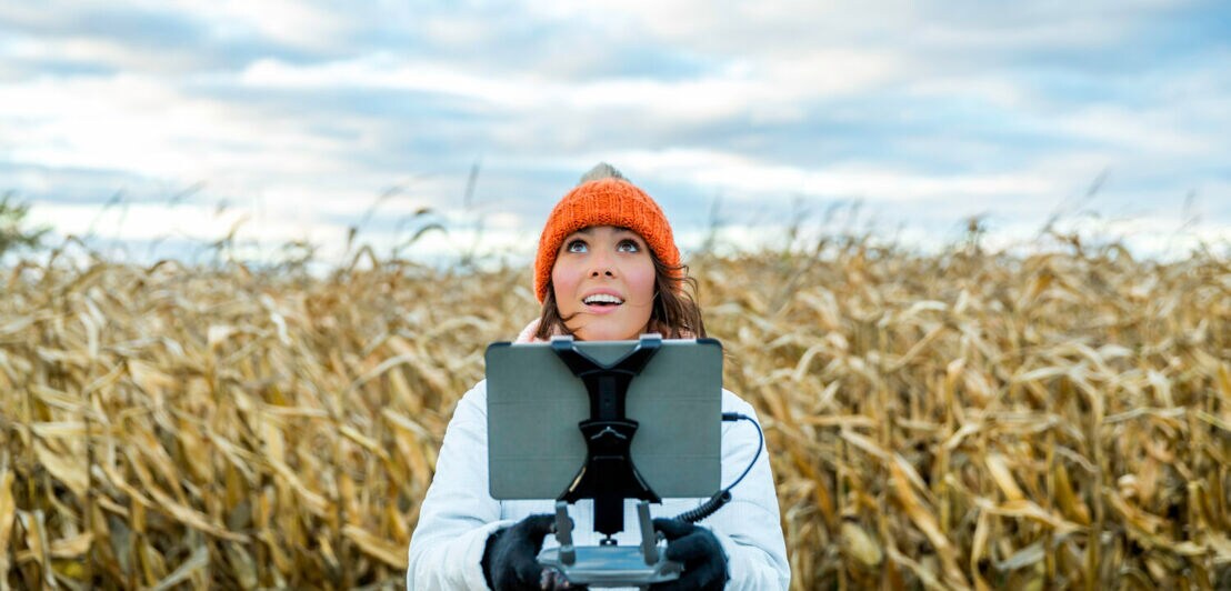 Eine Frau mit einer Fernsteuerung für eine Drohne in einem Feld