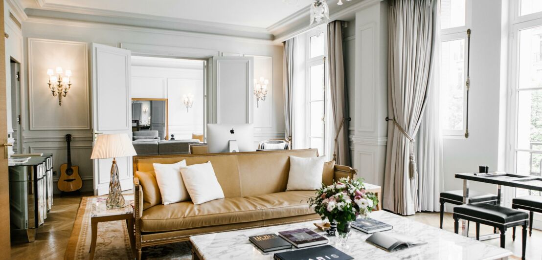 Ein Couchtisch mit einer Marmorplatte und ein braunes Ledersofa stehen In der Hotelsuite des Le Royal Monceau.