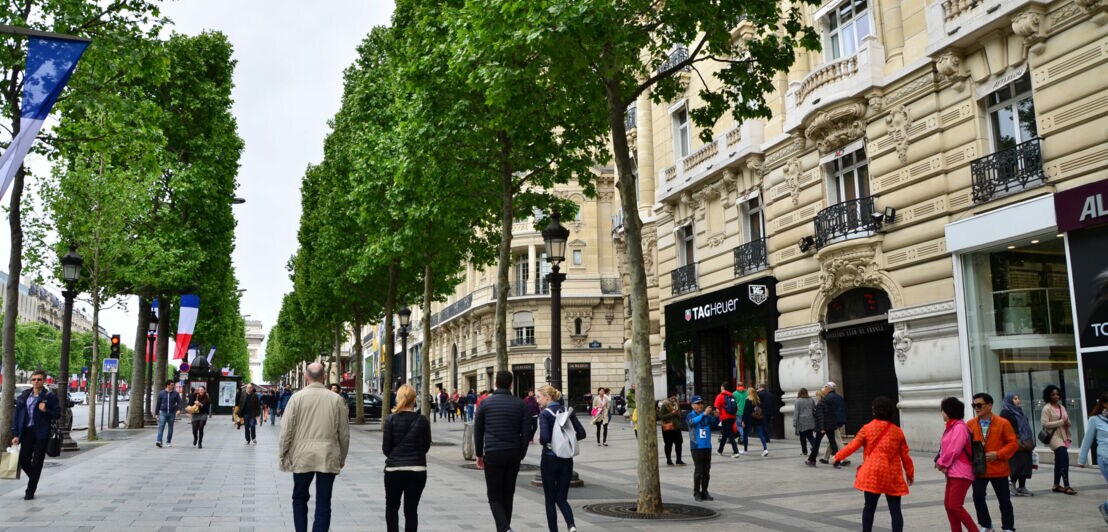 Mehrere Menschen flanieren über die Einkaufsstraße Champs-Élysées.