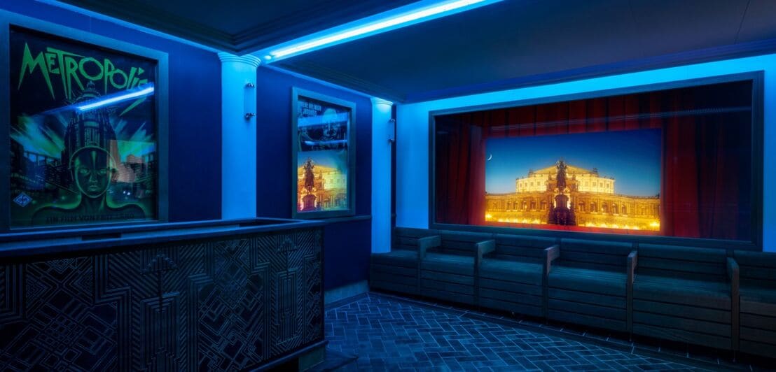Blau beleuchtete Sauna im Stil eines Kinos mit Leinwand und Filmplakaten an der Wand