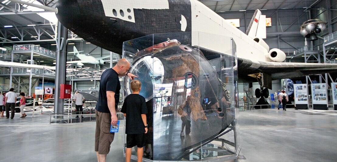 Zwei Menschen sehen sich das original Spaceshuttle Buran im Technik Museum Speyer an.