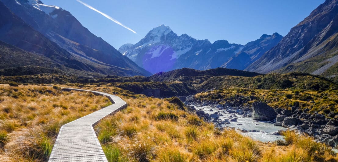 Wilde Landschaft des Mount-Cook-Nationalparks mit Bergpanorama, durch die ein Holzsteg führt