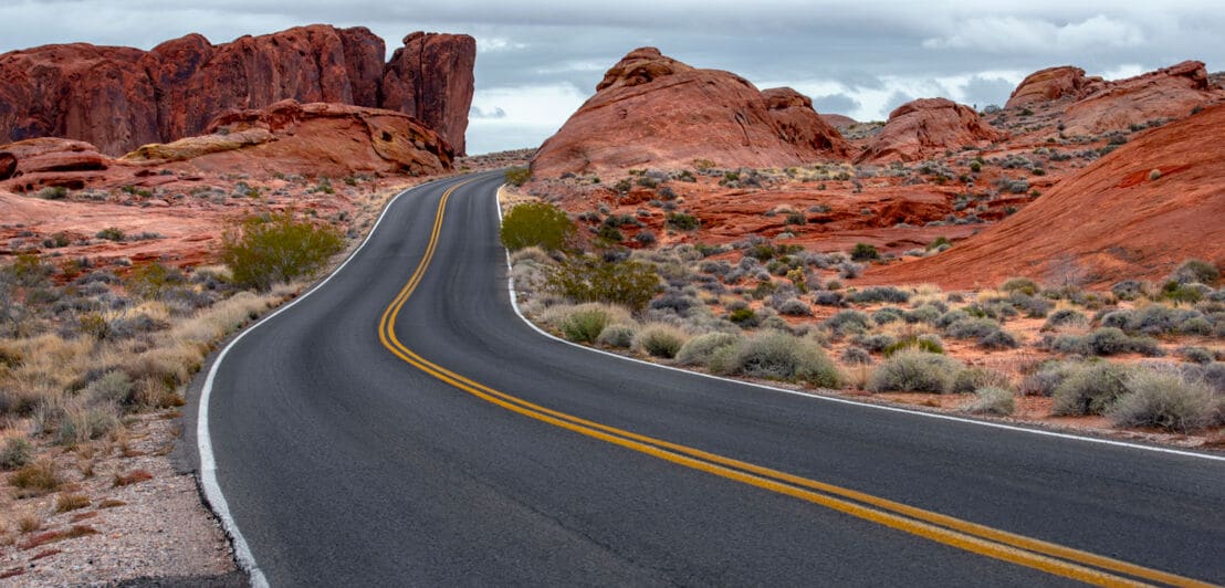 US-amerikanische Landstraße führt durch rote Felswüste.