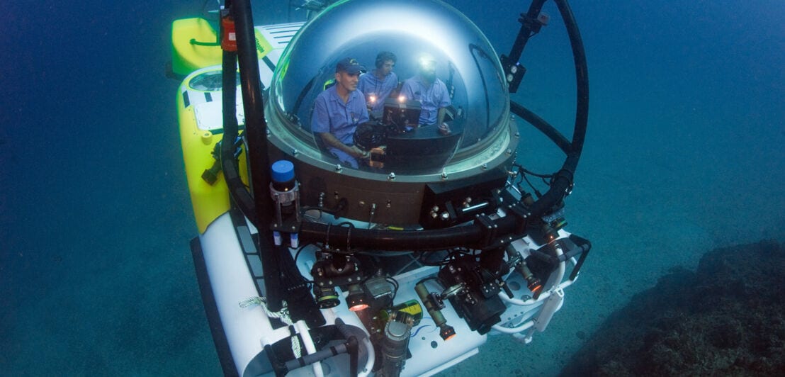 Das Forschungstauchboot DeepSee mit Glaskuppel, in der mehrere Personen sitzen.