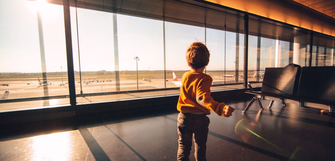 Rückansicht eines Jungen, der in einem Wartebereich am Gate eines Flughafens läuft