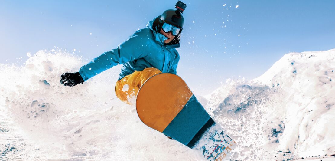 Ein Mensch beim Snowboarding trägt Helm mit Actioncam.