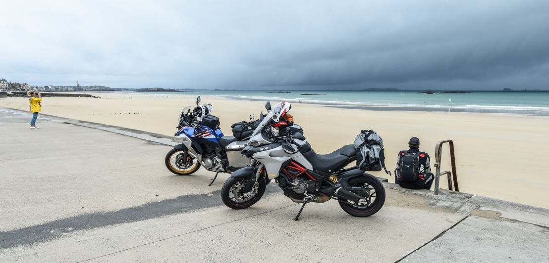 Zwei Motorräder auf einer Straße vor einem Strand