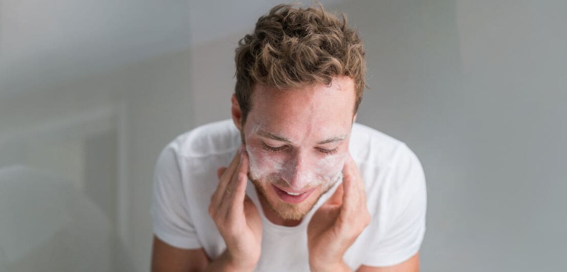 Ein Mann reinigt sich zu Hause sein Gesicht mit Reinigungsseife.