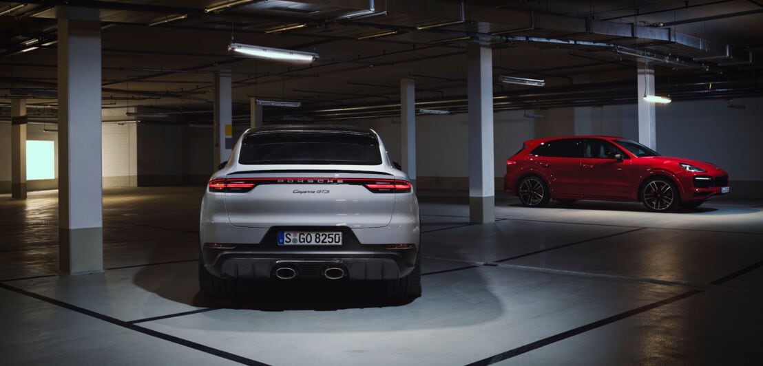 Ein weißer und ein roter Porsche in einer Tiefgarage