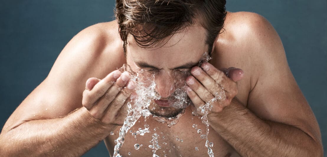 Ein Mann befeuchtet sein Gesicht mit Wasser aus seinen Händen