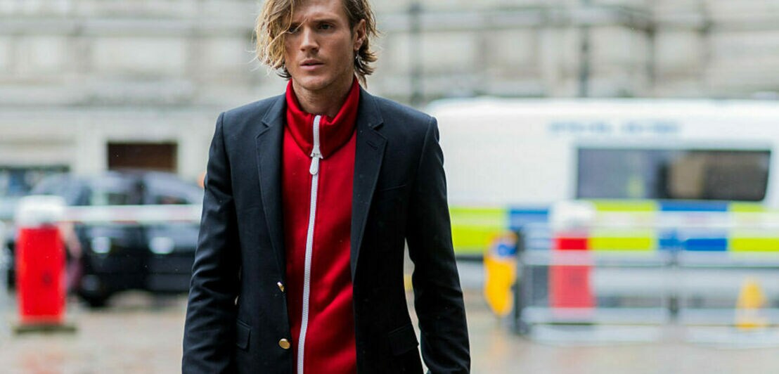 Model und Musiker Dougie Poynter trägt eine rote Trainingsjacke in Kombination mit einem schwarzen Blazer.