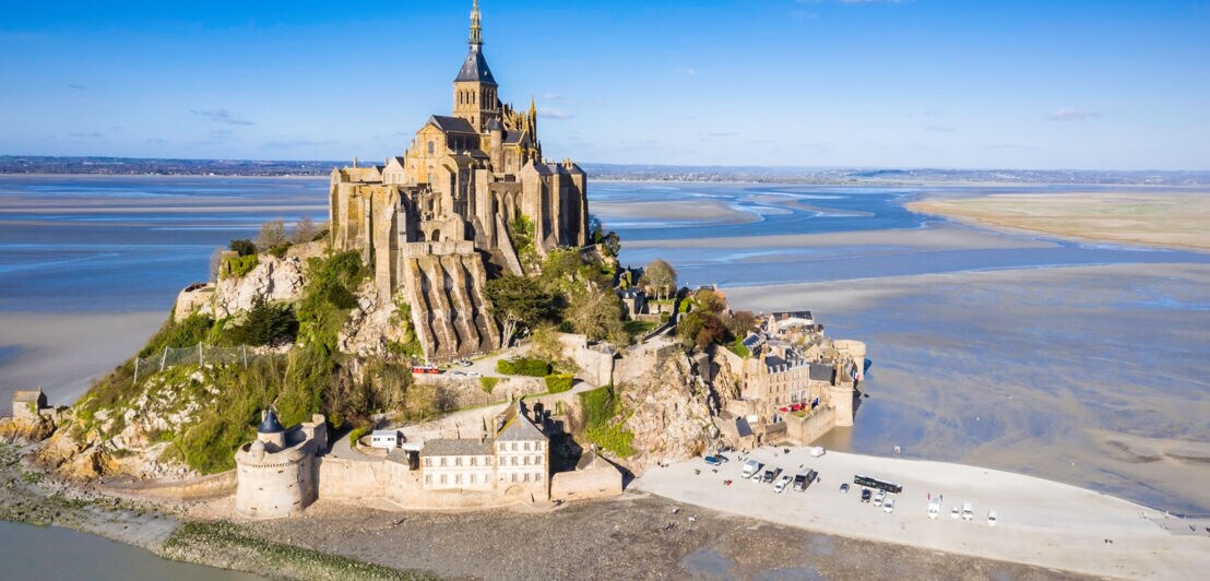 Die Klosterinsel Mont-Saint-Michel umgeben von Wasser und Sand.