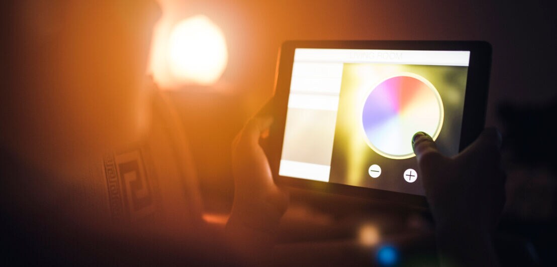 Eine Person steuert über das Tablet die Farben der Beleuchtung.