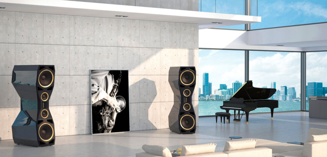 Zwei Divin-Majestic-Lautsprecher in einem Wohnzimmer neben einem Konzertflügel