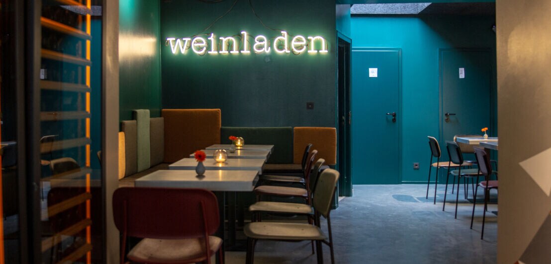 Restauranttische unter dem beleuchteten Schriftzug weinladen in Köln
